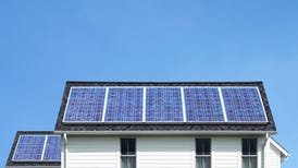Solar panels atop a white house.