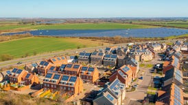 Homes with roof top solar panels in front of a large solar farm.