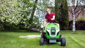 young man riding lawn mower on grassy field