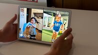 Hands holding an Android tablet with kids on the screen